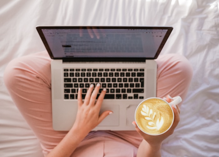 Hands on laptop keyboard with coffee